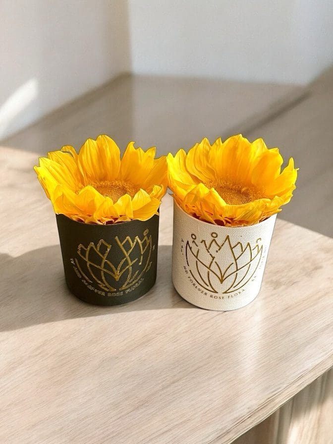 Two cups with yellow flowers on a table.